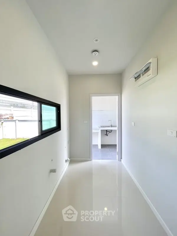 Bright hallway leading to a modern kitchen with sleek white finishes.