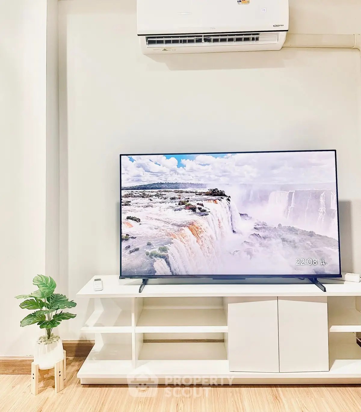 Modern living room with sleek TV and air conditioner, showcasing stylish decor and wooden flooring.