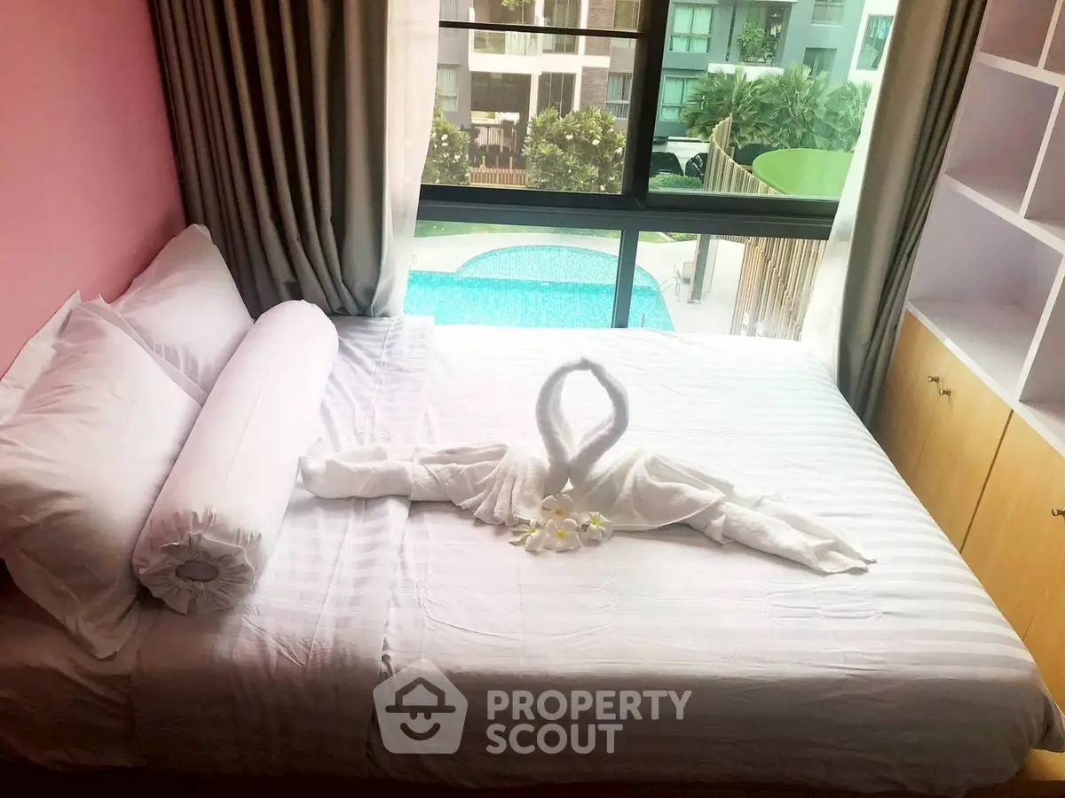 Cozy bedroom with pool view, featuring elegant swan towel decor on bed.