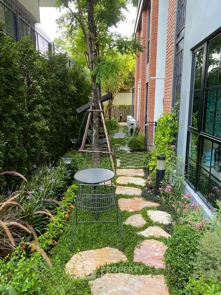 Charming garden pathway with lush greenery and modern outdoor seating, perfect for relaxation and nature lovers.