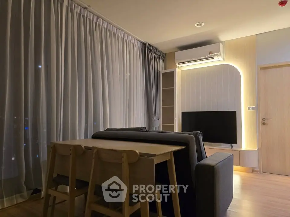 Modern living room with stylish furniture and ambient lighting, featuring a cozy dining area and sleek TV setup.