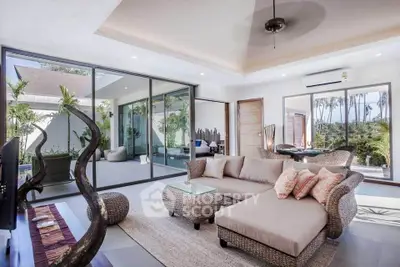 Luxurious living room with modern decor and large glass doors opening to a lush garden view.