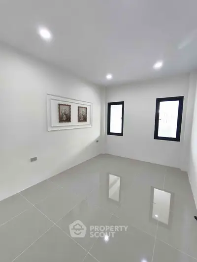 Spacious modern room with glossy tiled floor and minimalist decor, featuring large windows for natural light.