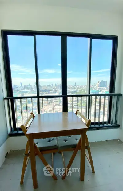 Stunning city view from a modern apartment balcony with a cozy dining setup.