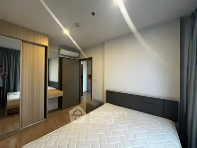 Modern bedroom with wooden flooring, built-in wardrobe, and air conditioning unit.