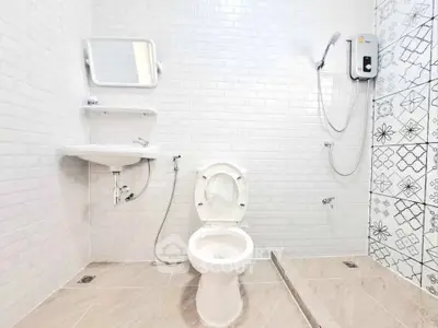 Modern bathroom with white tiles, shower, and toilet in minimalist design.