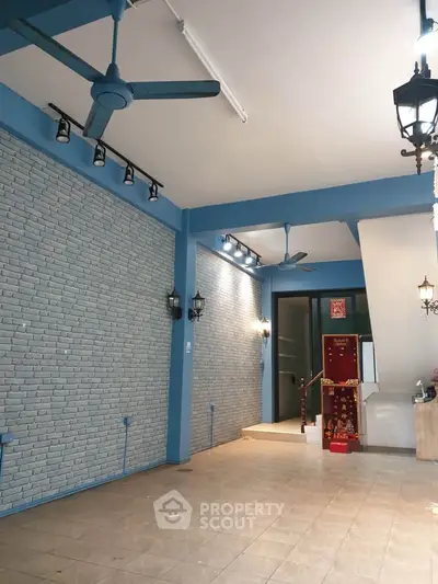 Spacious modern entrance with stylish brick wall and ceiling fans, perfect for welcoming guests.