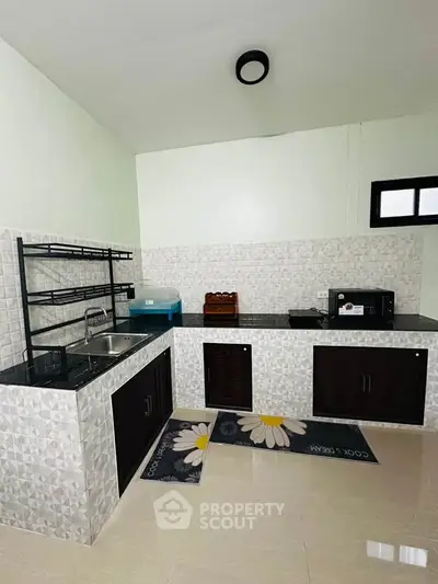 Modern kitchen with sleek countertops and stylish backsplash, featuring a sink and microwave for convenient cooking.