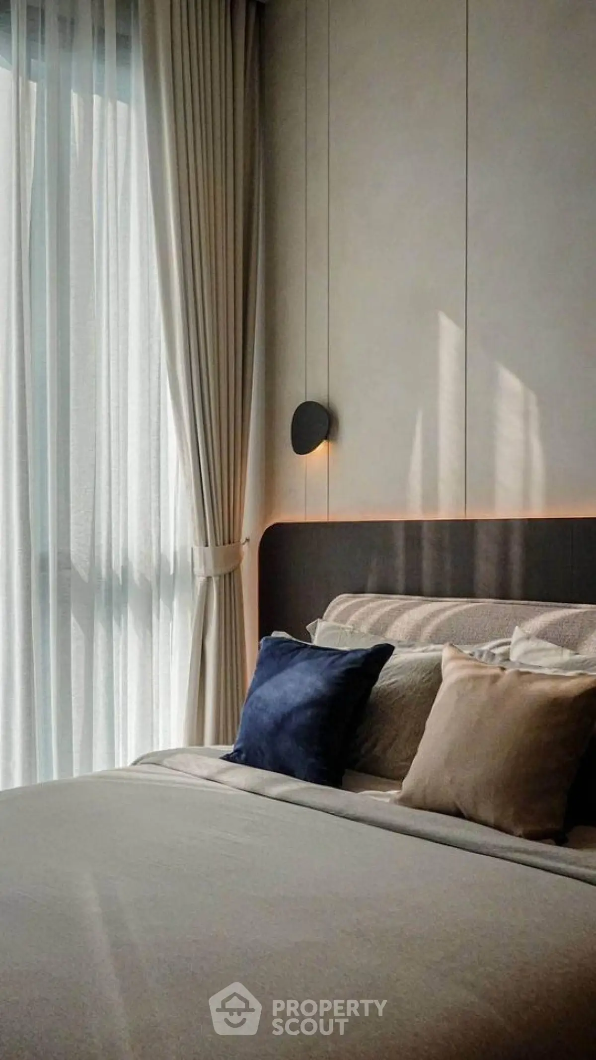 Luxurious bedroom with elegant decor and soft lighting, featuring plush pillows and floor-to-ceiling curtains.