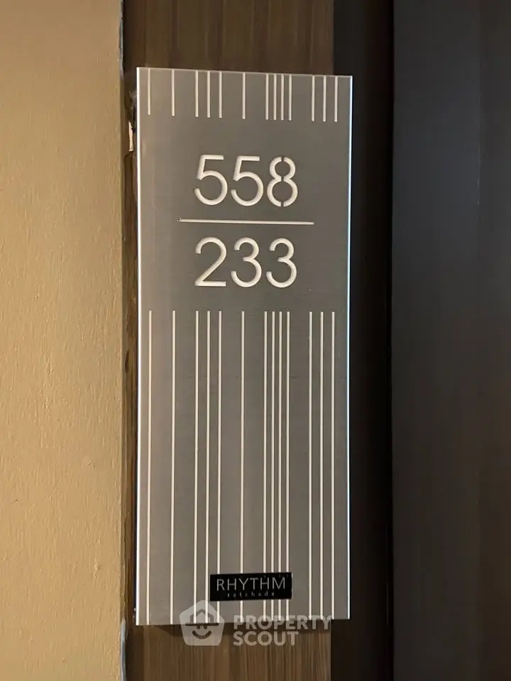 Modern apartment door sign with stylish design and room number 558/233 at Rhythm building.