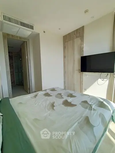 Modern bedroom with stylish decor and wall-mounted TV in a contemporary apartment.