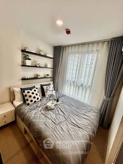 Cozy modern bedroom with stylish decor and large window offering natural light.
