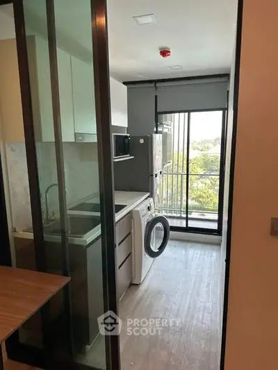 Modern kitchen with washing machine and balcony view in sleek apartment