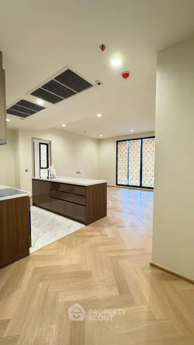 Spacious modern living room with wooden flooring and large windows in a luxury apartment.