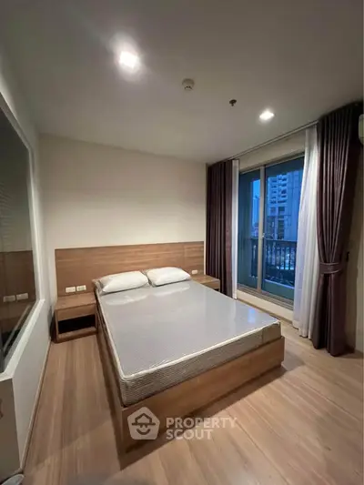 Modern bedroom with wooden flooring and large window offering city view