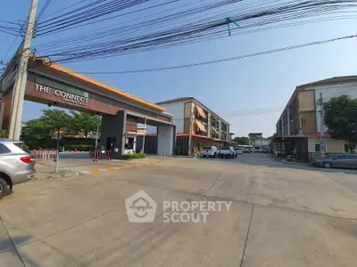 Modern residential complex entrance with spacious parking and contemporary architecture.