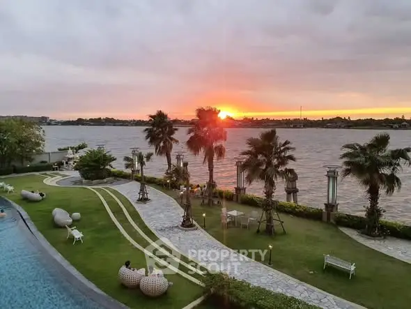 Stunning riverfront view with lush garden and sunset, ideal for luxury living.