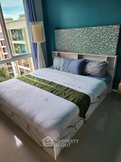 Modern bedroom with stylish decor and large window offering a scenic view of the building exterior.