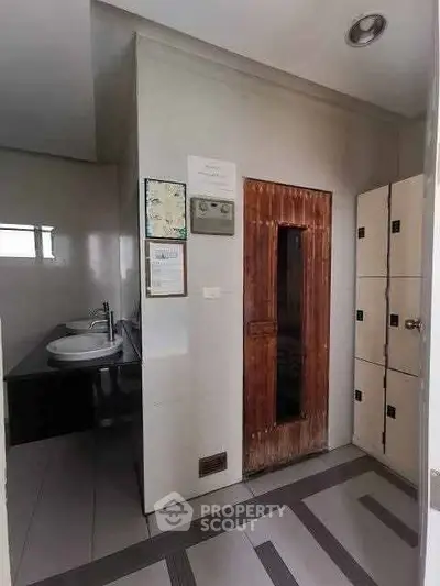 Modern bathroom with dual sinks and wooden sauna door in sleek design.