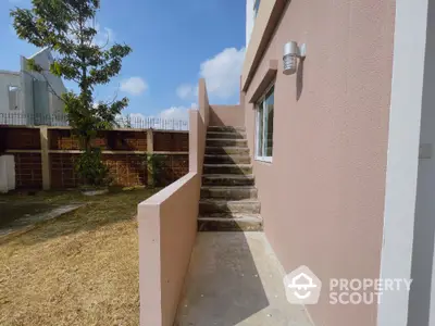 Modern exterior staircase leading to upper level with pink walls and outdoor lighting