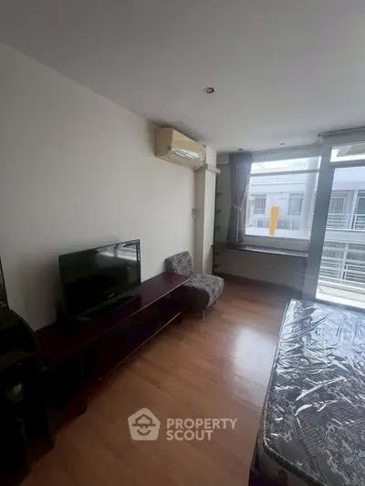 Spacious bedroom with modern furnishings and large window offering natural light.