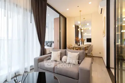 Modern open-plan living room with elegant decor and dining area, featuring floor-to-ceiling windows.