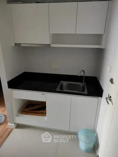 Compact modern kitchen with sleek white cabinets and black countertop