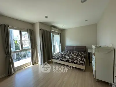 Spacious bedroom with large windows and modern furnishings in a bright apartment.