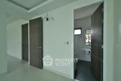 Modern interior with open doors leading to bathroom and other rooms, showcasing sleek design and neutral tones.