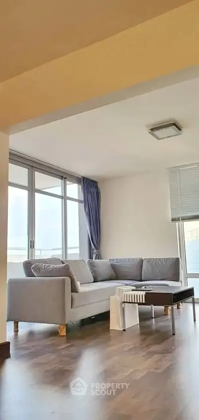 Spacious living room with modern gray sofa and large windows offering natural light.