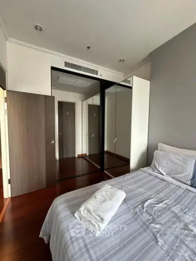 Modern bedroom with mirrored wardrobe and wooden flooring