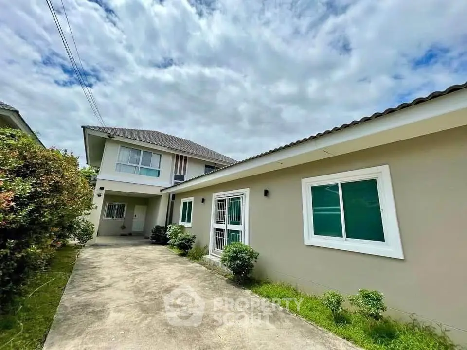 Charming suburban home with spacious driveway and lush greenery under a bright sky.