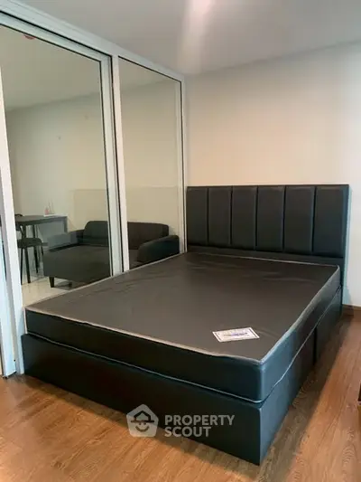 Modern bedroom with sleek black bed and glass partition, perfect for urban living.