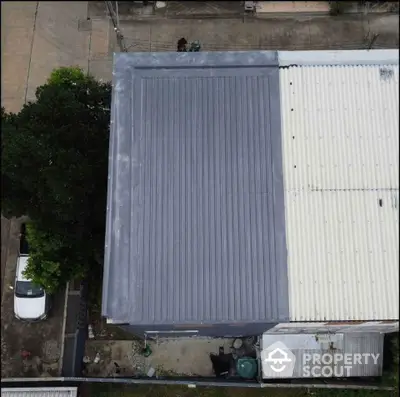 Aerial view of residential building with metal roof and adjacent parking area.