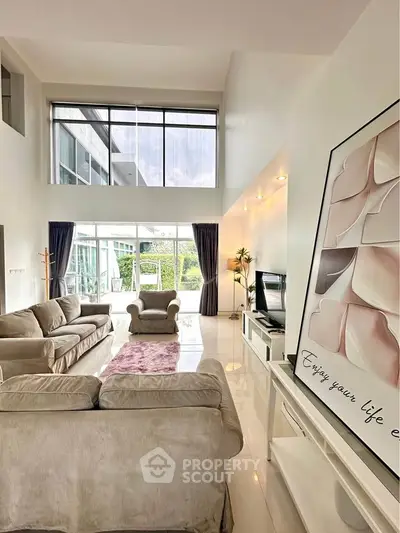 Spacious modern living room with high ceilings and large windows offering natural light and garden view.