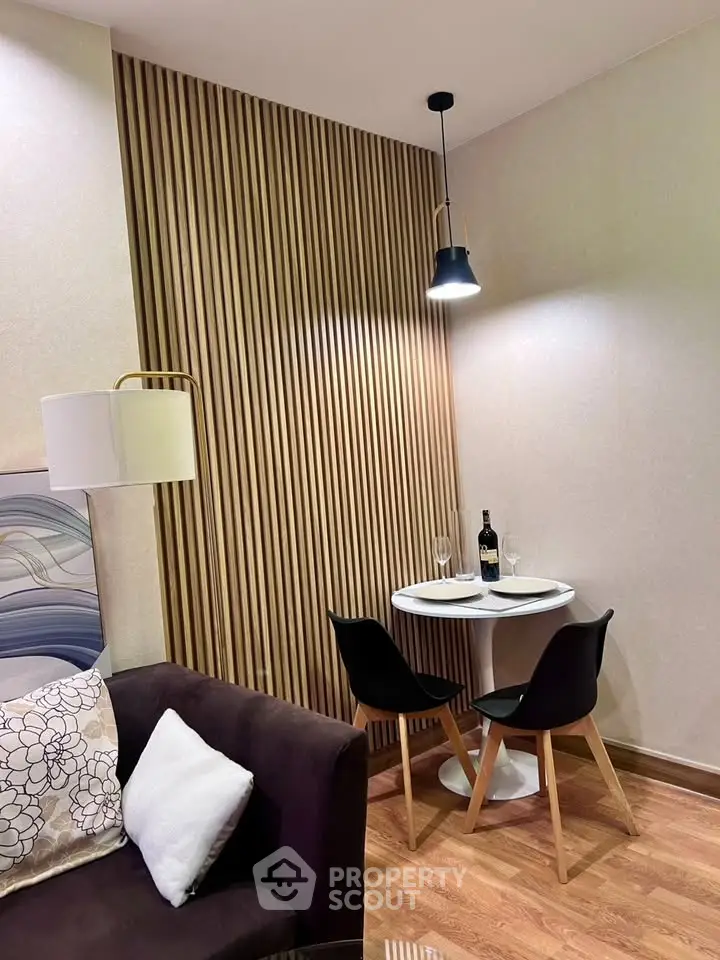 Cozy modern living room corner with stylish wooden paneling and intimate dining setup.