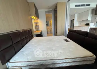 Modern bedroom with cozy bed, open layout leading to kitchen and bathroom, ideal for urban living.