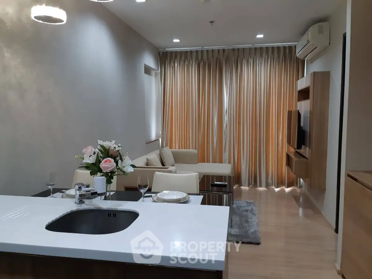 Modern living room with elegant decor and open kitchen layout, featuring cozy seating and stylish lighting.