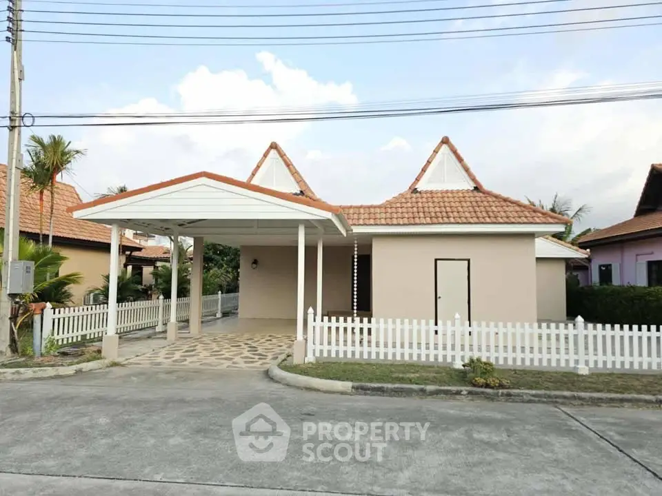 Charming single-story home with unique roof design and white picket fence