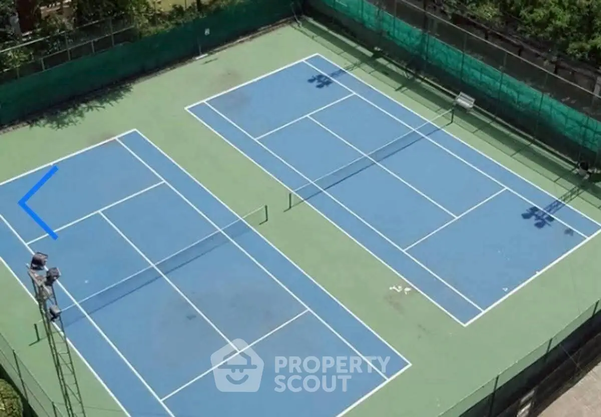 Aerial view of dual tennis courts in a residential complex, perfect for sports enthusiasts.
