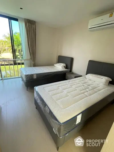 Modern bedroom with twin beds and large window offering natural light and garden view.