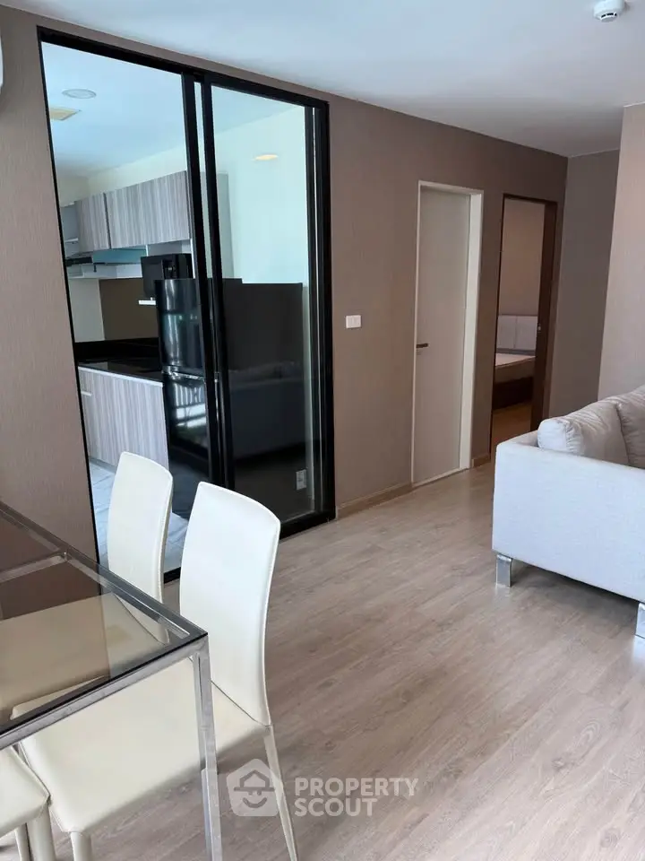 Modern open-plan living room with sleek kitchen and dining area, featuring stylish furniture and wooden flooring.