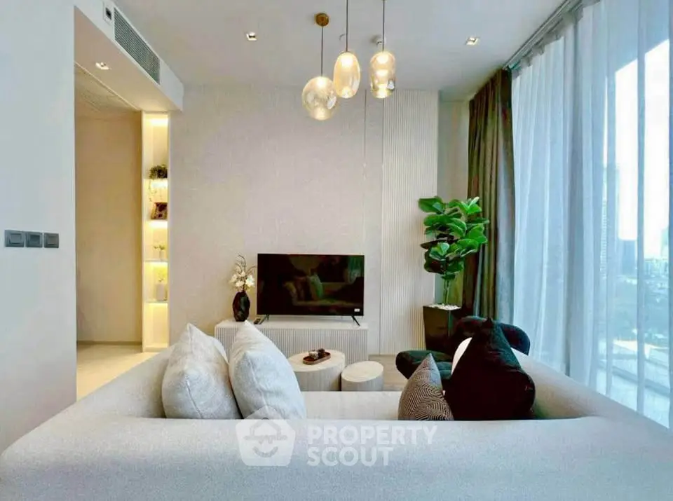 Modern living room with cozy sofa, stylish lighting, and large windows offering city views.