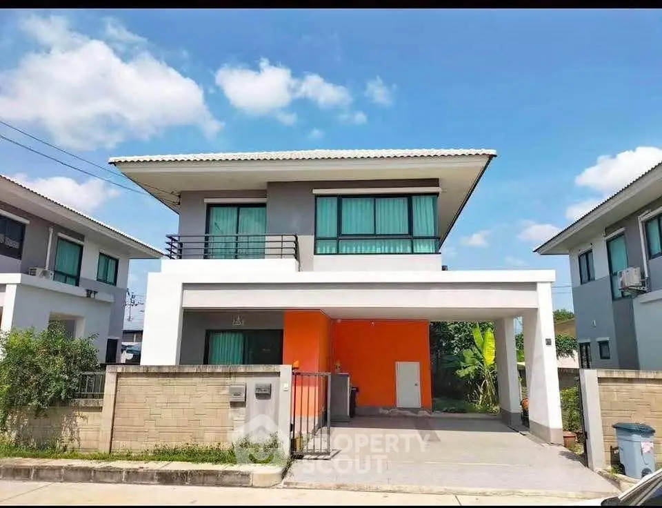 Modern two-story house with vibrant orange accent wall and spacious driveway