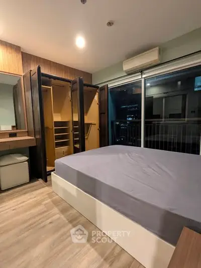 Modern bedroom with open wardrobe and city view balcony.