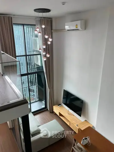 Modern loft-style living room with high ceiling and large windows offering city views.