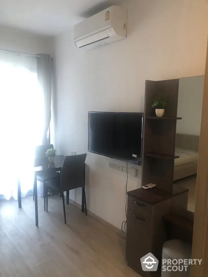 Modern living room with wall-mounted TV and air conditioning in a cozy apartment.