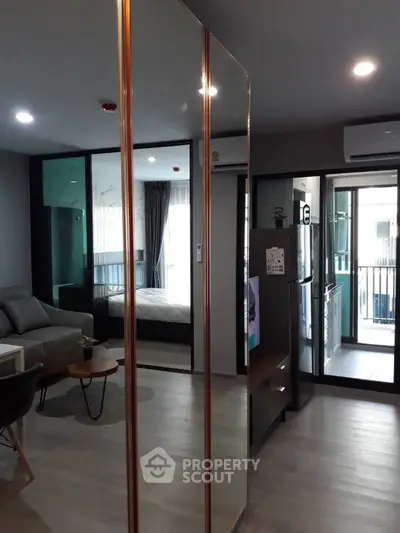 Modern apartment interior with open layout, featuring living room, bedroom, and kitchen with balcony access.