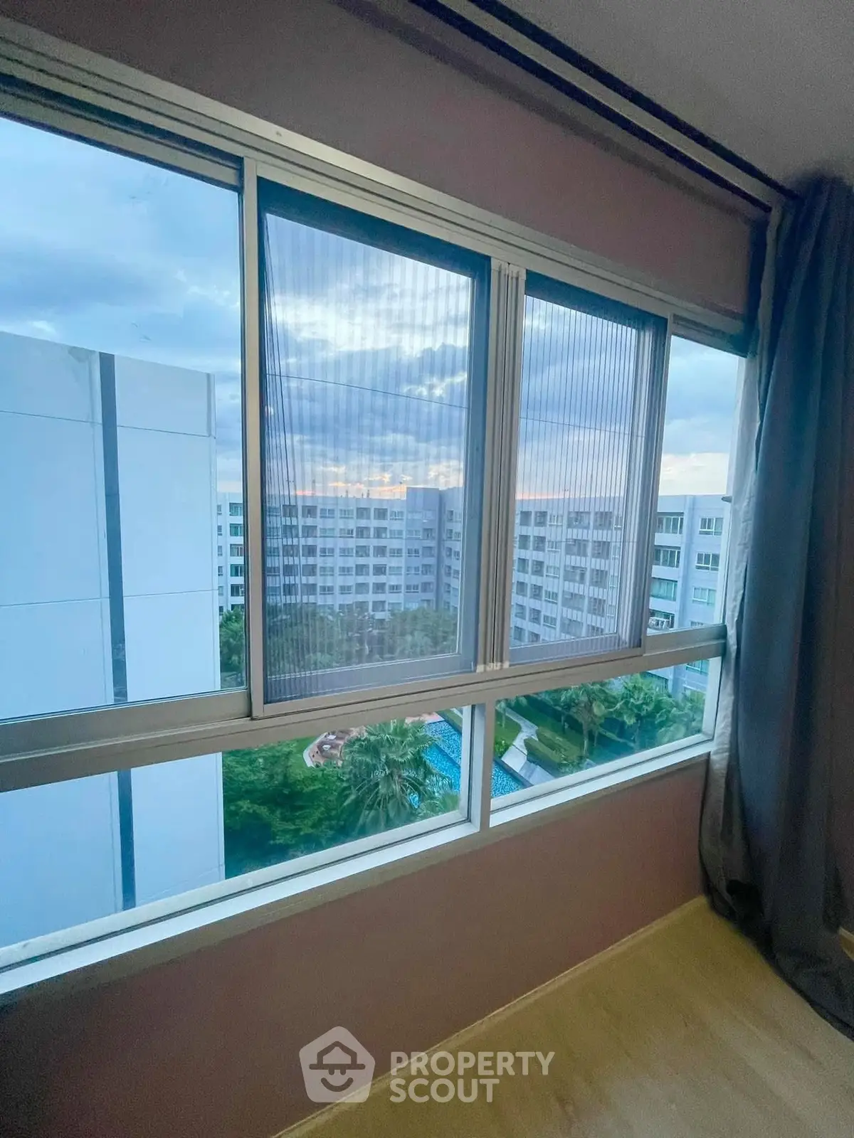 Stunning high-rise view from modern apartment window overlooking lush greenery and cityscape.
