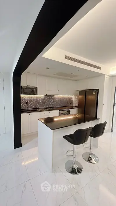 Modern kitchen with sleek black and white design, featuring an island and stylish bar stools.